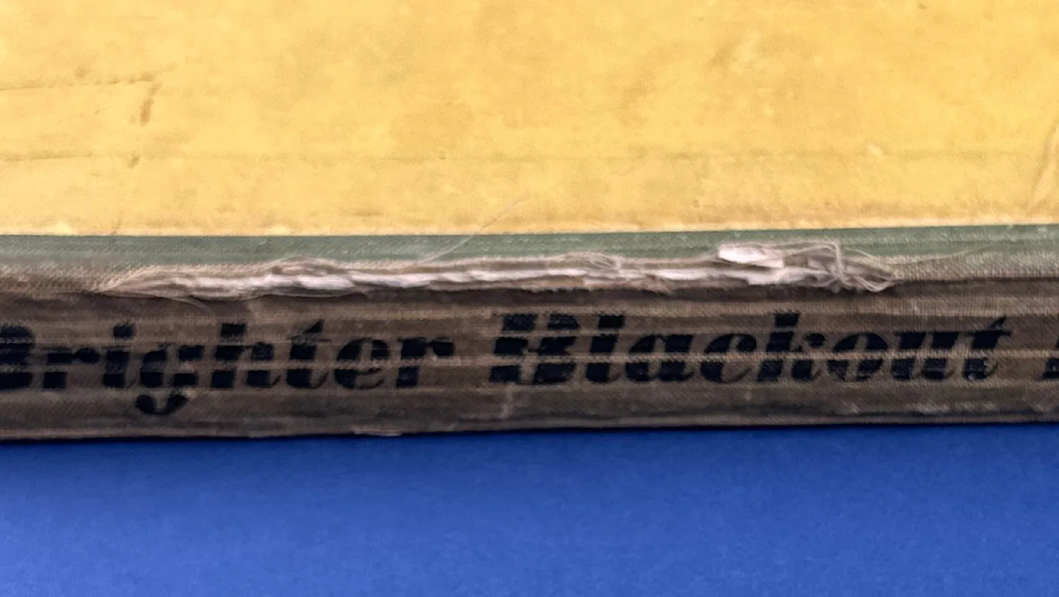 WW2 Brighter Blackout Book (1939–1940) by Howard Thomas, original wartime edition with cloth strip spine and printed boards closeup of spine and damage