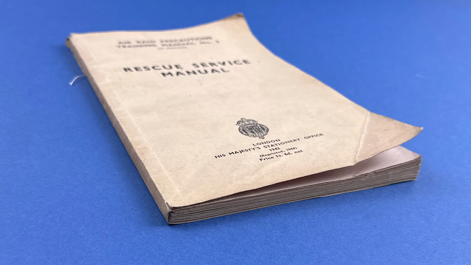 Angled front cover view of the WW2 ARP Rescue Service Manual showing curled corner and overall cover condition.