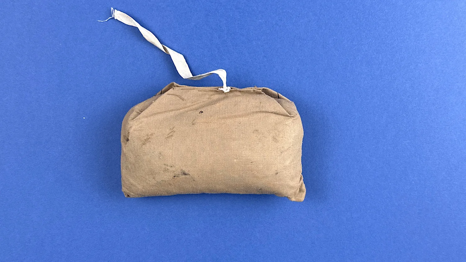 Rear view of the unopened 1938 ARP Shell Dressing with original khaki cloth wrap and attached tie