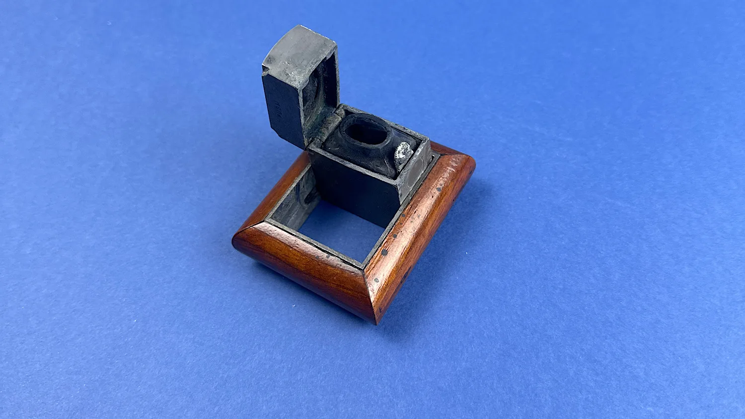 Angled view of the De La Rue campaign folding inkwell partially unfolded within its wooden frame