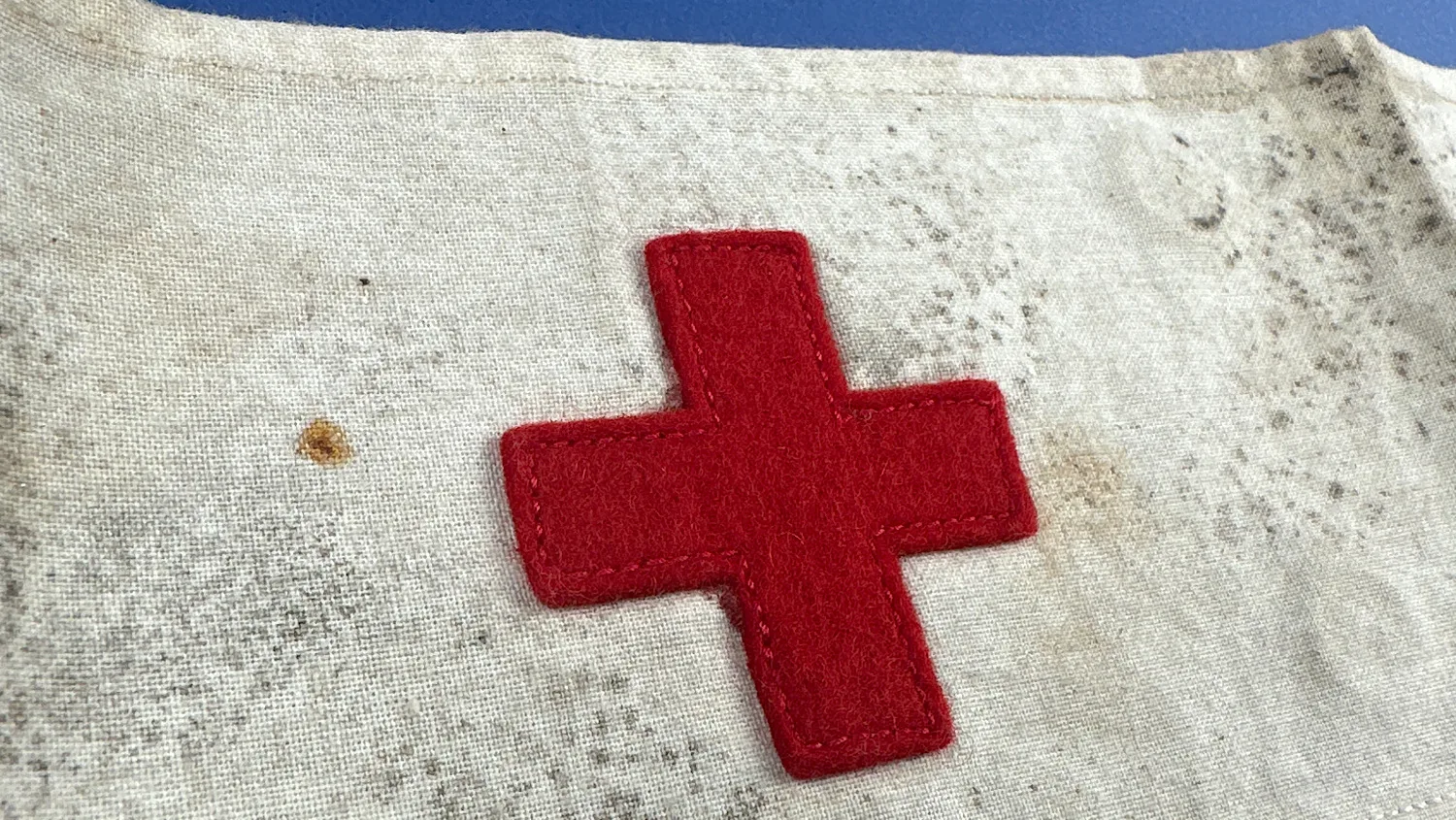 Close up of sewn red felt cross showing stitching detail and fabric wear