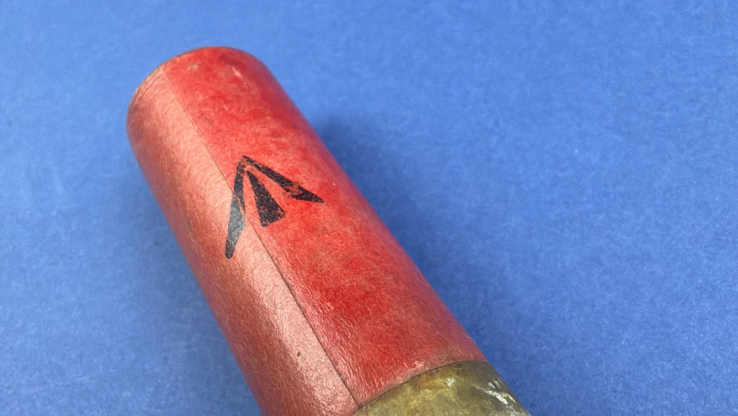 Close up of red paper case with black directional marking on WW2 British 12 Bore solid ball cartridge