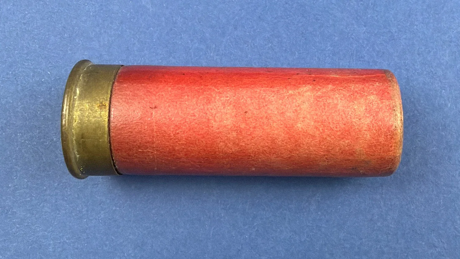 Side profile of red paper case and brass head on WW2 British Eley Kynoch 12 Bore cartridge