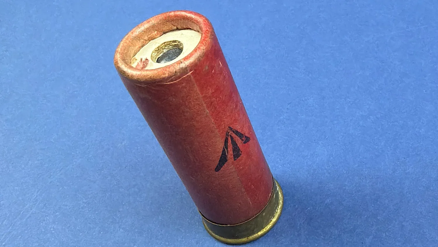 Angled view of WW2 British Eley Kynoch solid ball cartridge showing red paper body and visible projectile