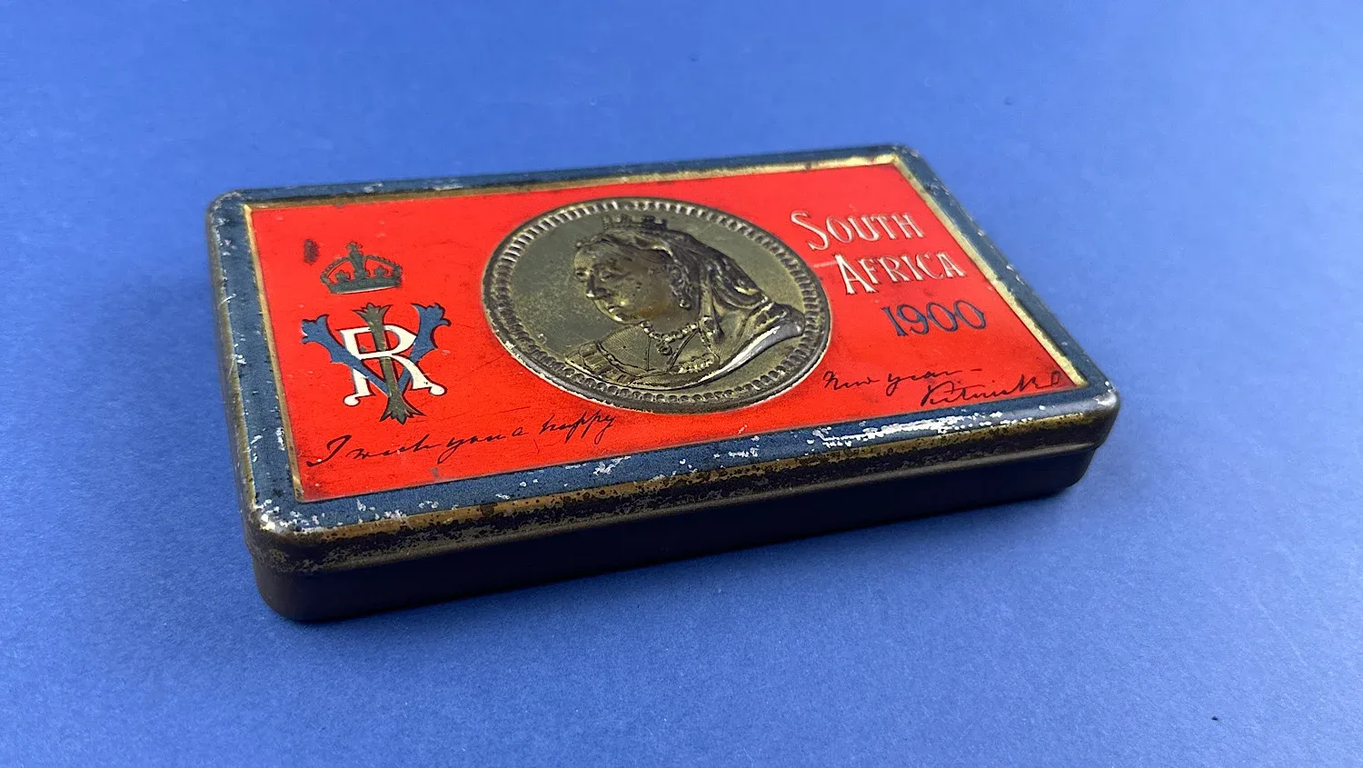 Angled view of Boer War chocolate tin showing South Africa 1900 design and edge wear