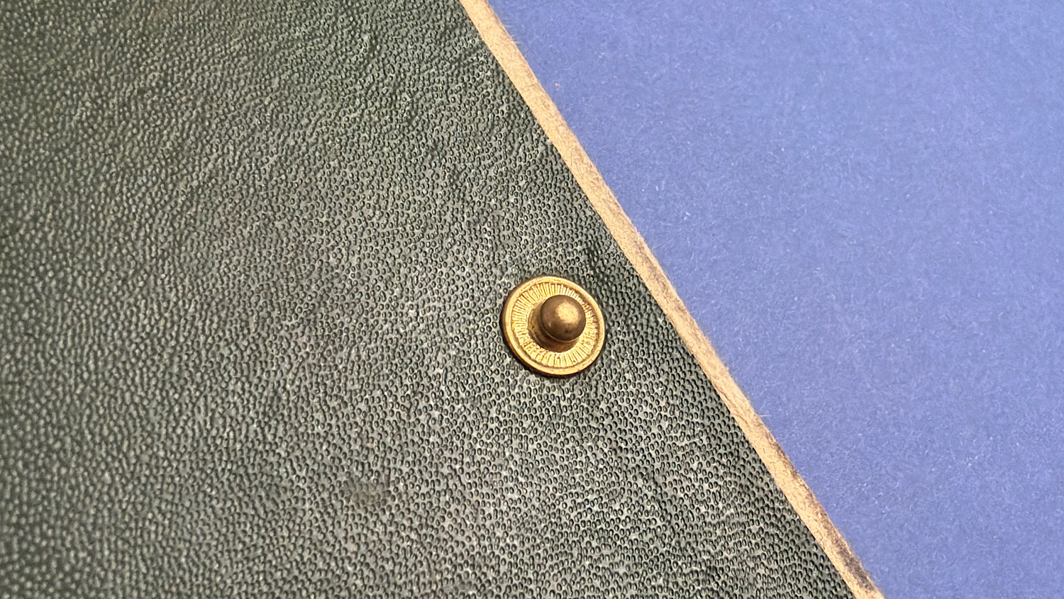 Close up of brass press stud fastening on green cover of WW2 British Drivers M.T. Notes sleeve