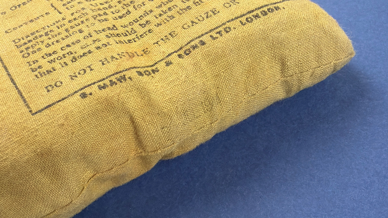 Side view of original WW2 British First Field Dressing showing sealed edge and intact wrapper construction
