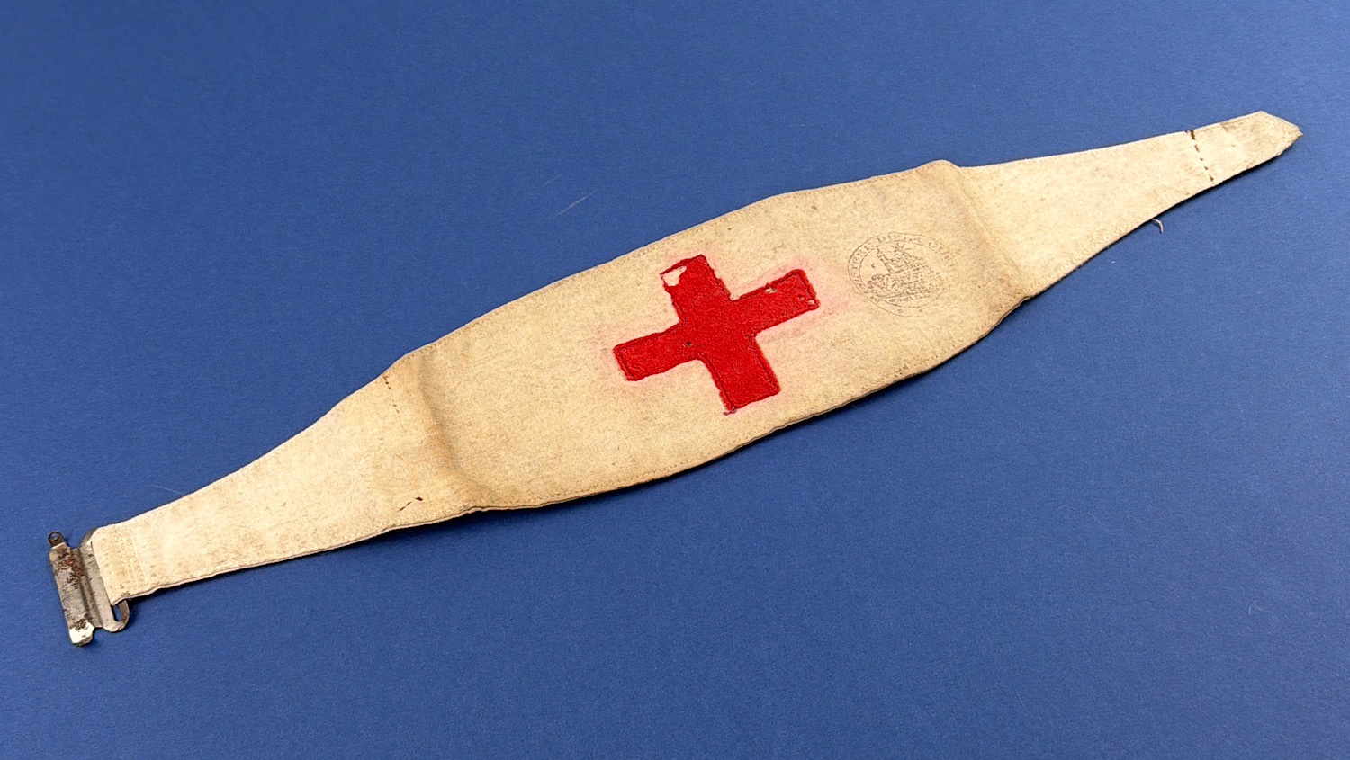Angled view of original French WW1-era Red Cross medical brassard showing stitched construction and period metal fastening.