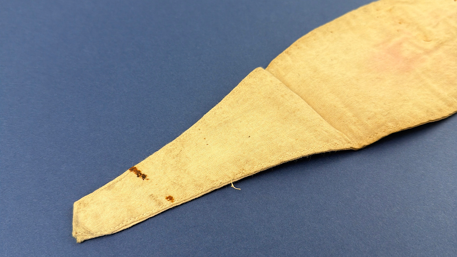 Close-up of the tapered end of the brassard showing age-related staining and light rust marks.