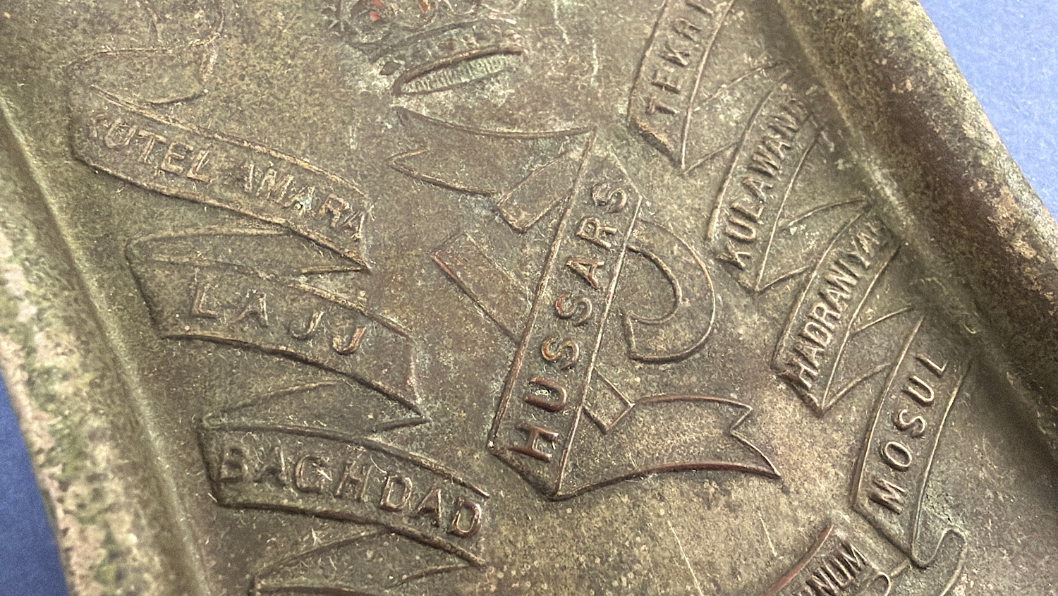 Close-up of the 13th Hussars regimental badge with battle honours including Kut-el-Amara, Lajj and Baghdad.