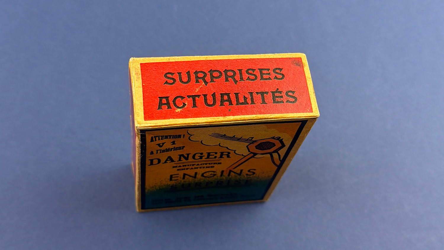 Top view of the original sealed WW2 French anti-Hitler propaganda dexterity toy displaying the French slogan "Surprises Actualités".