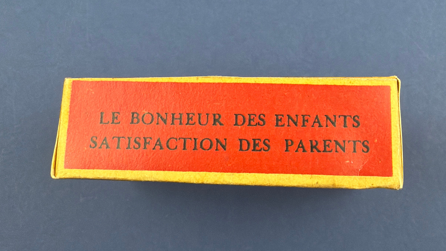 Original side view of the sealed WW2 French anti-Hitler propaganda dexterity toy showing the "Le Bonheur des Enfants, Satisfaction des Parents" slogan.