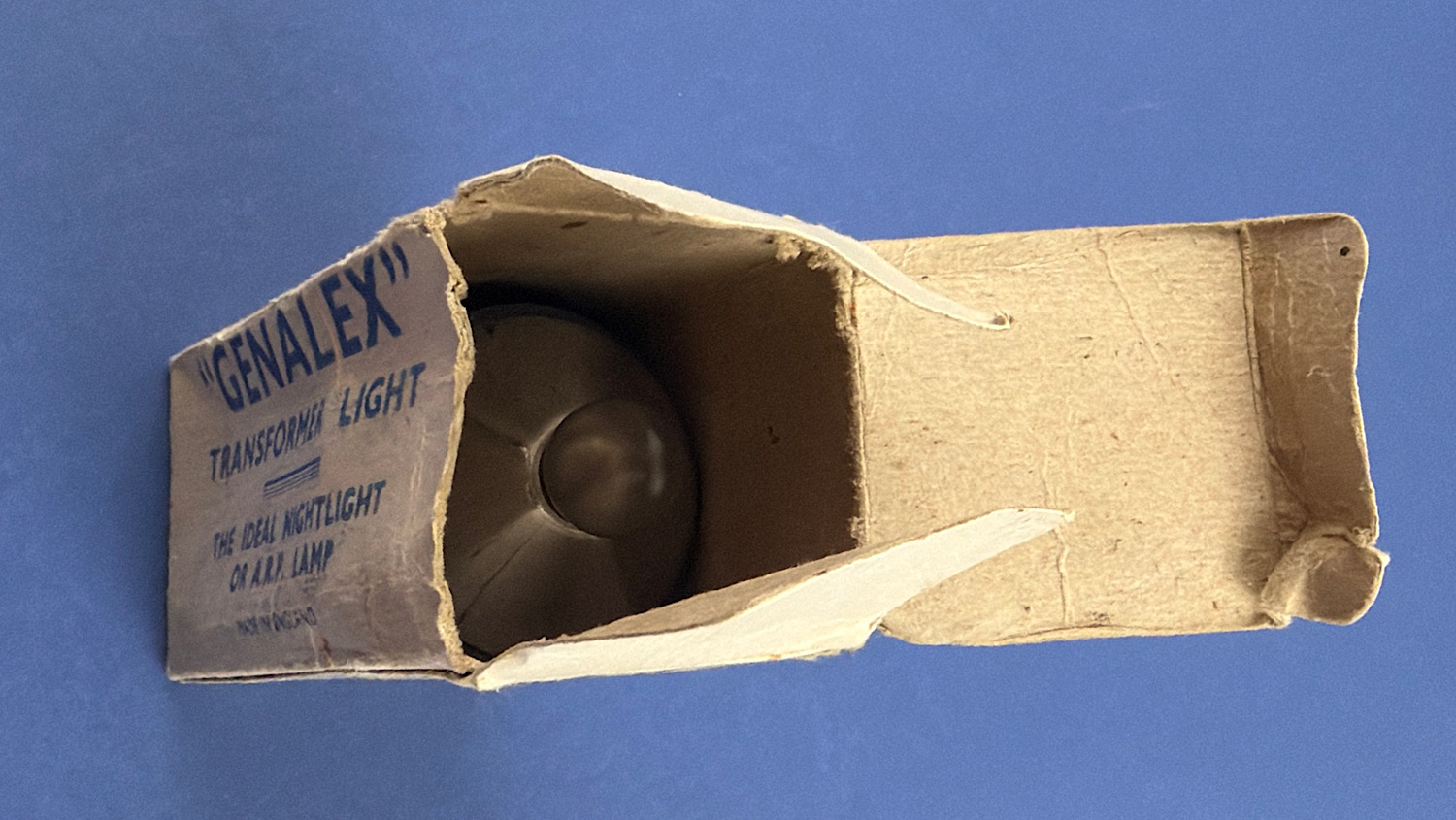 Original WW2 Genalex transformer light shown inside its original cardboard box with the original frosted bulb visible.