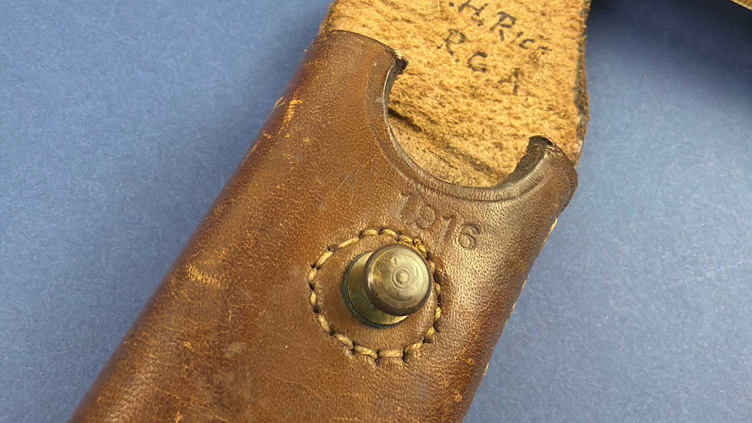 Detail of the WW1 1916 dated broad arrow marked leather case showing the original brass press stud and military stampings.