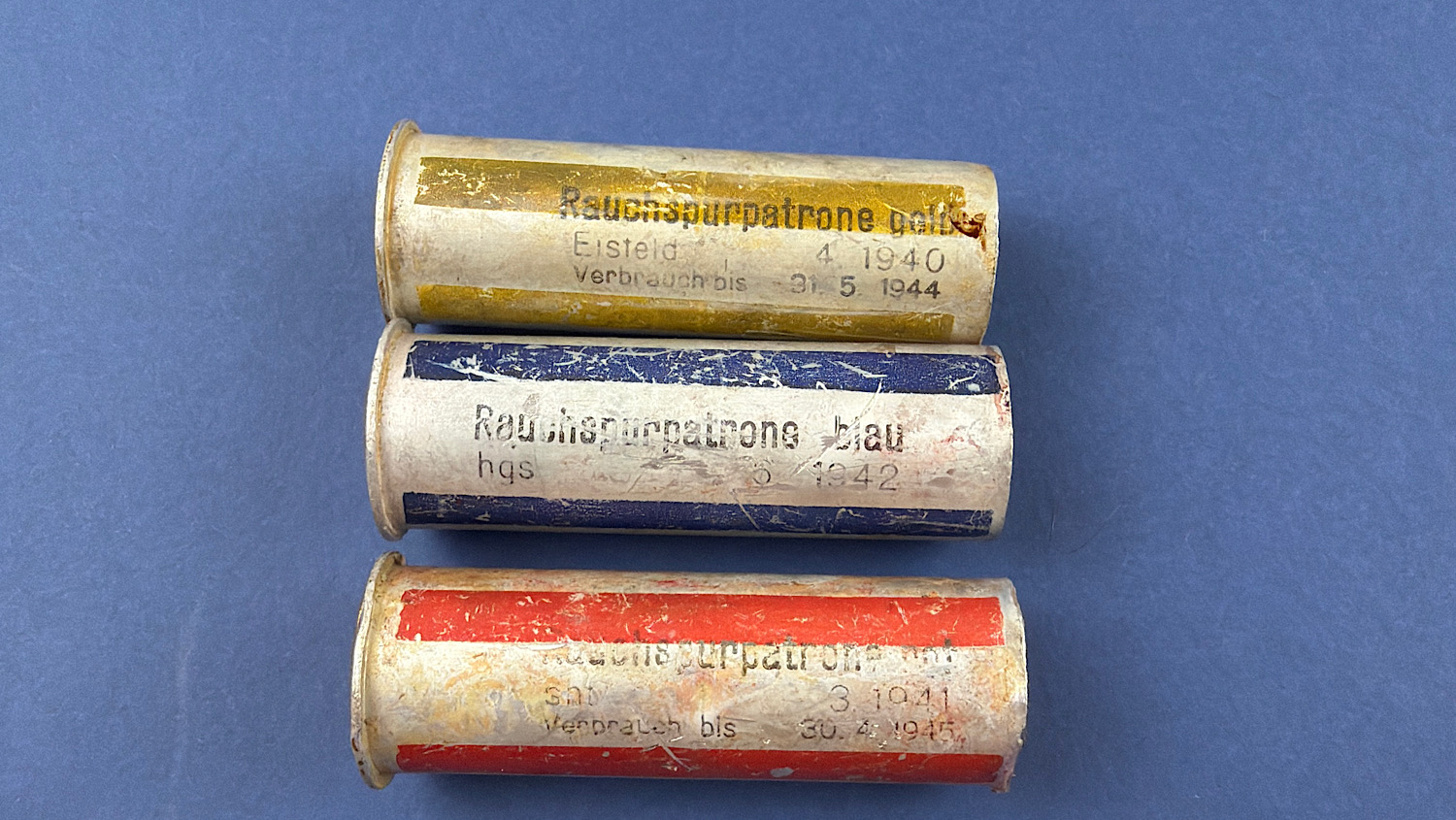 Three original WW2 German inert smoke signal cartridges in yellow, blue and red with wartime labels and dated markings.