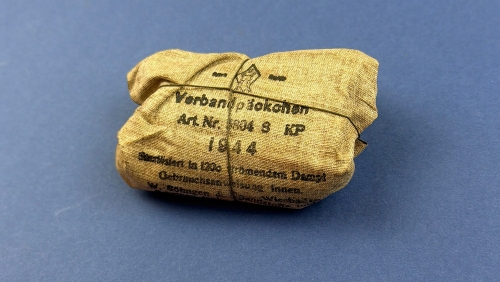 Original 1944 dated German WW2 Verbandpäckchen field dressing showing the intact outer wrapper with clear manufacturer's markings and original string tie.