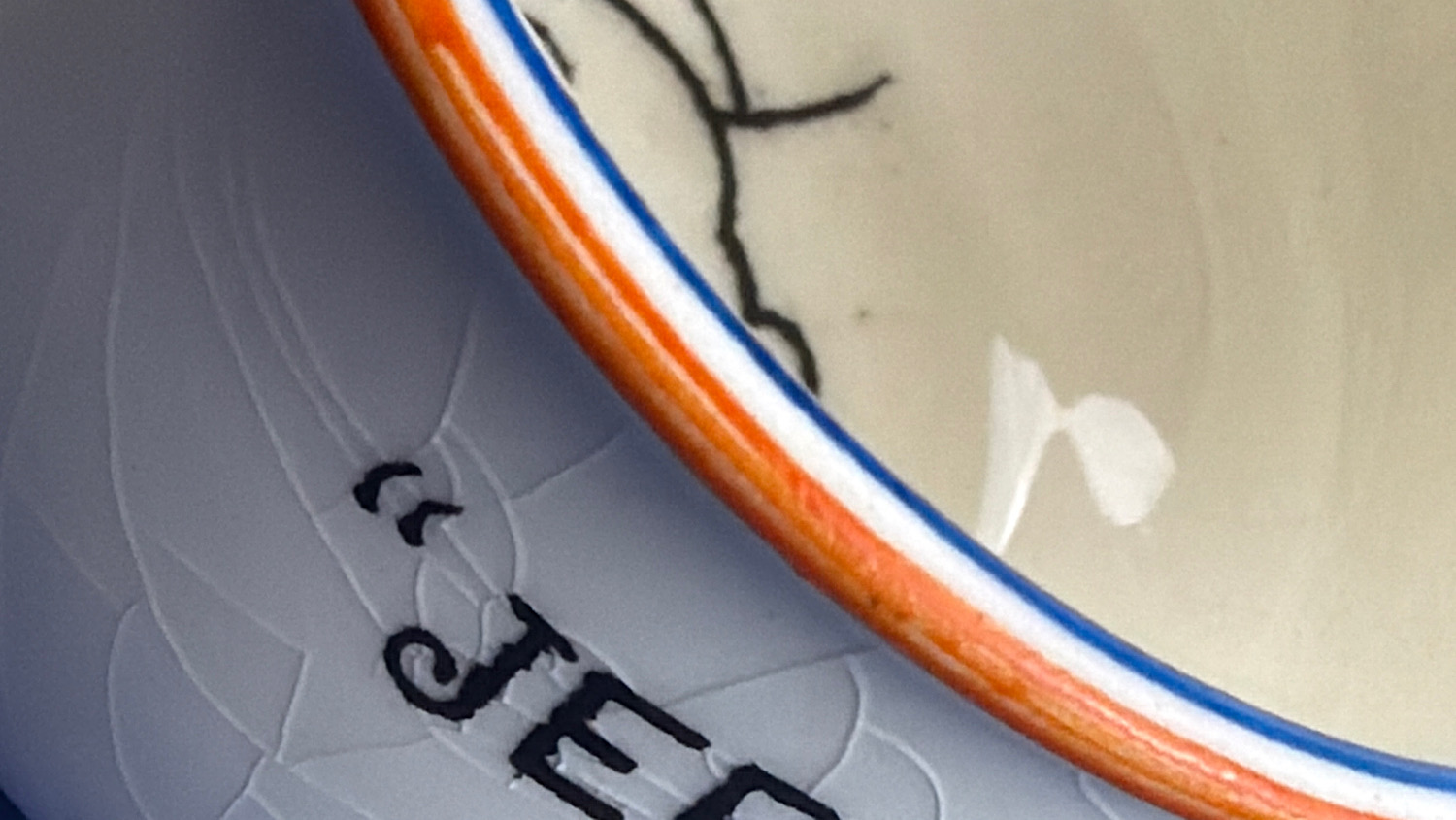 Close-up of the red and blue painted rim and glaze crazing on the WW2 Fieldings anti-Hitler chamber pot ashtray.