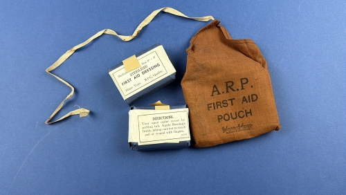 Original WW2 British ARP first aid pouch displayed with two unopened Mines Type sterilised first aid dressings.